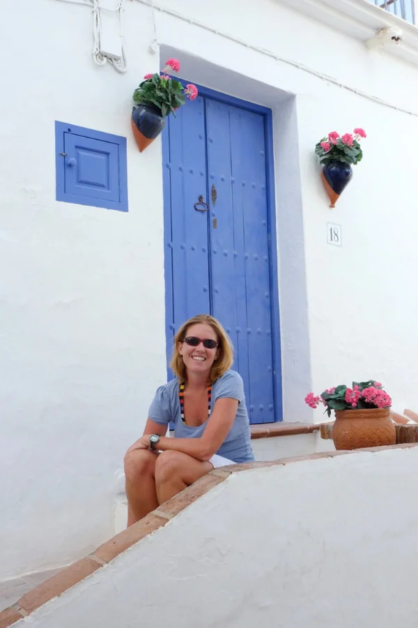 casey sitting on the steps of a white washed house with a blue door