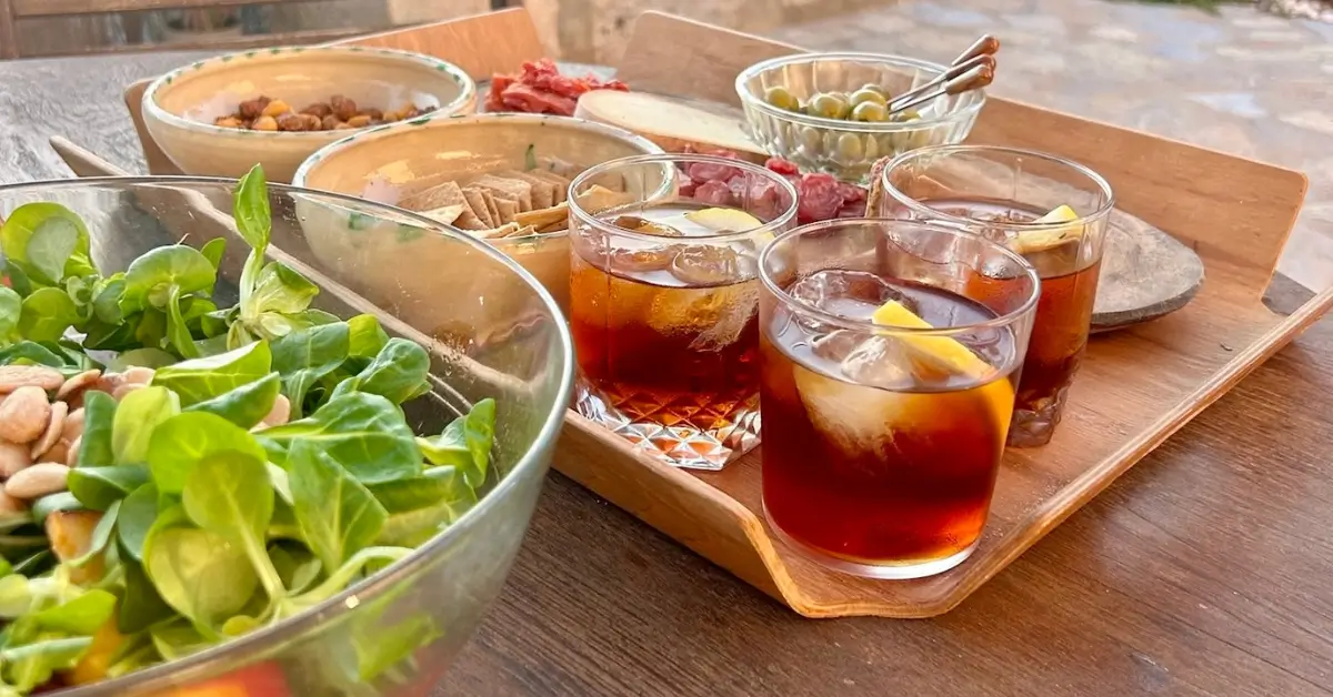 how to drink vermut like a spainard compressed glasses of vermut sitting on a wooden tray with accompaniments